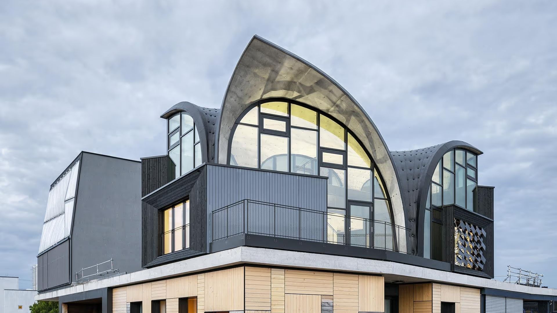 A building corner topped by a curved, glazed concrete shell roof unit
